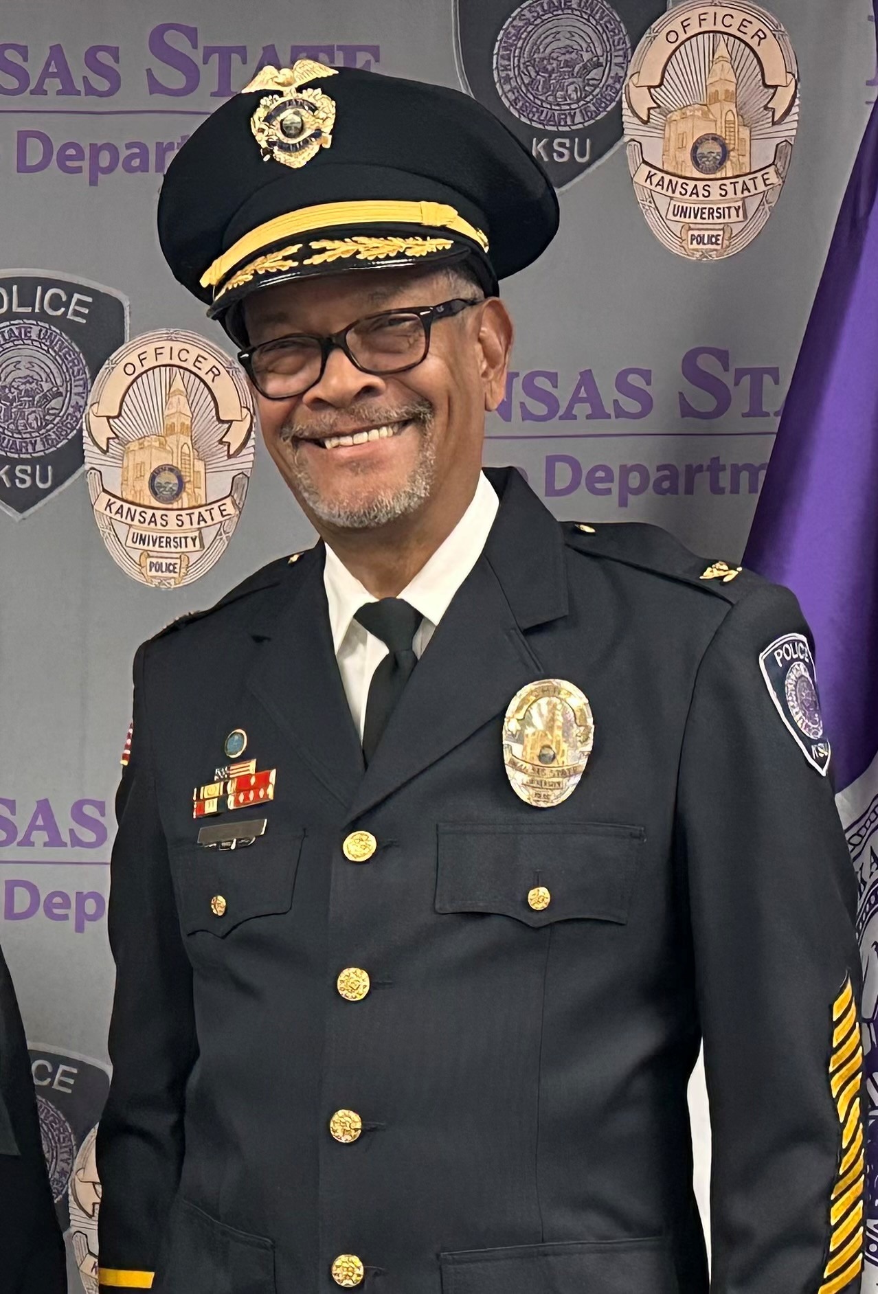 A police chief poses for a portrait while wearing the full navy "dress blues" police uniform.
