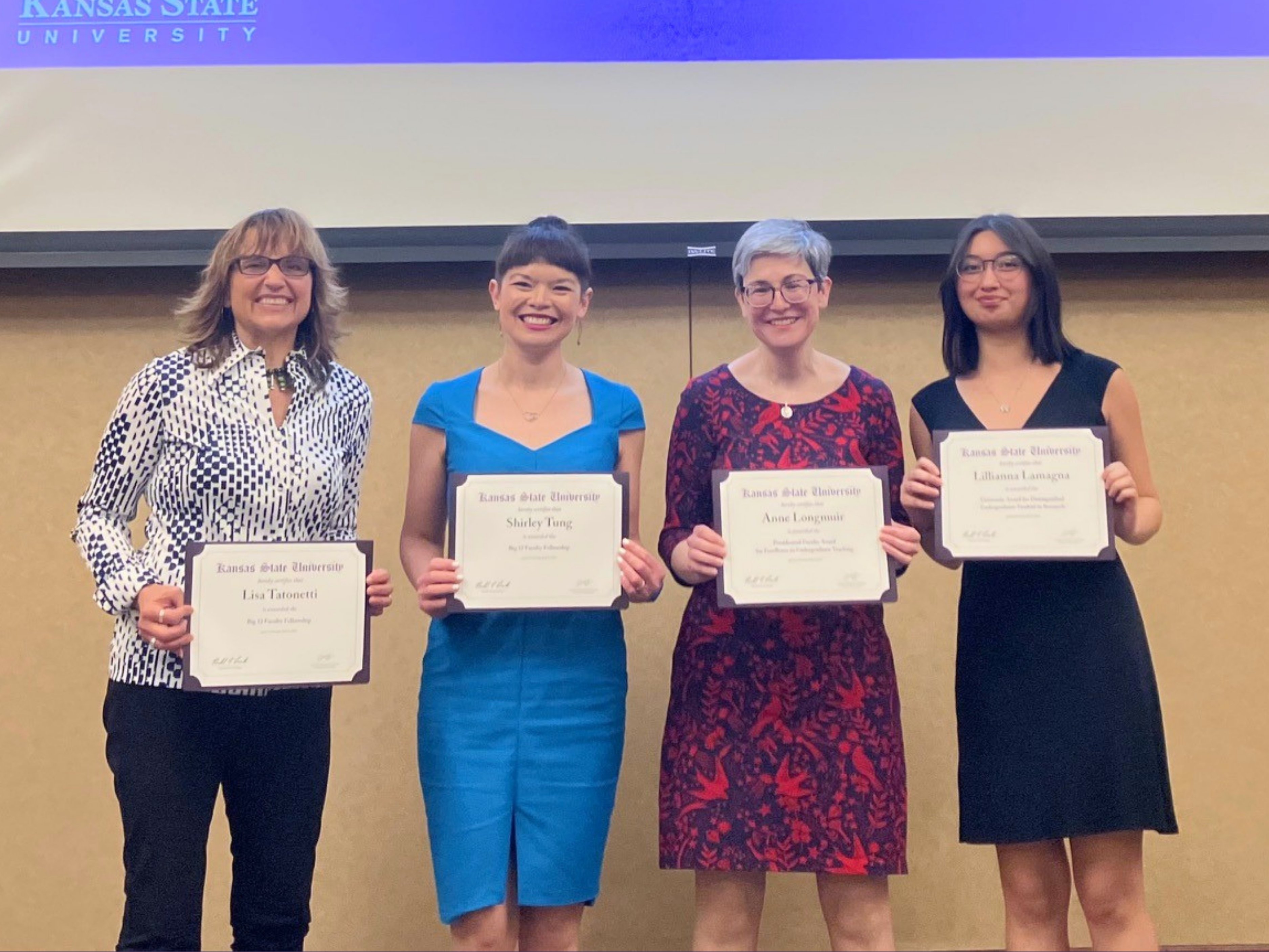 Four women holding certificates stand together during a Big 12 Fellowship award ceremony.