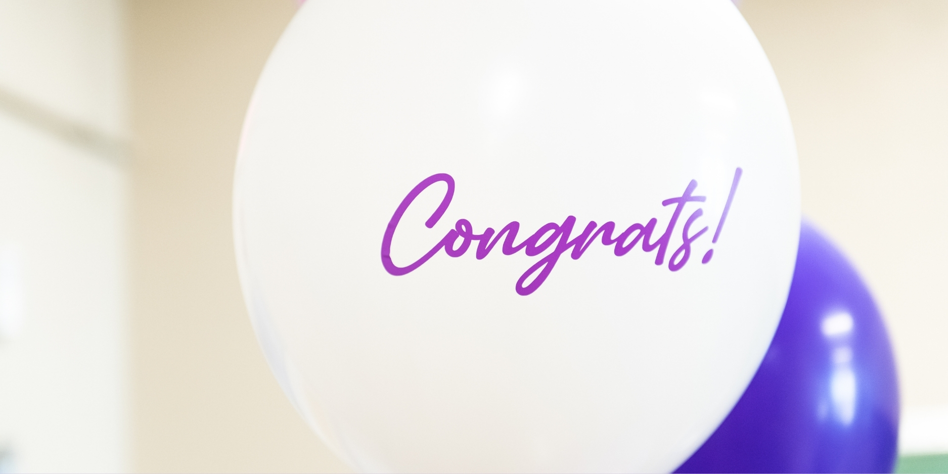 Closeup image of a white balloon with purple script writing saying 