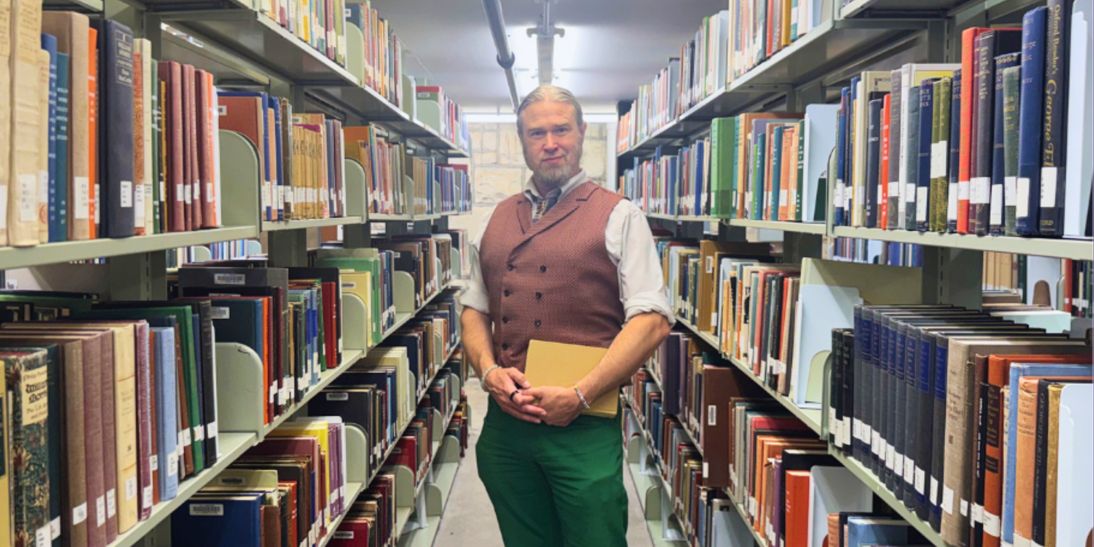 Dan Ireton poses in a row of books in the K-State Libraries