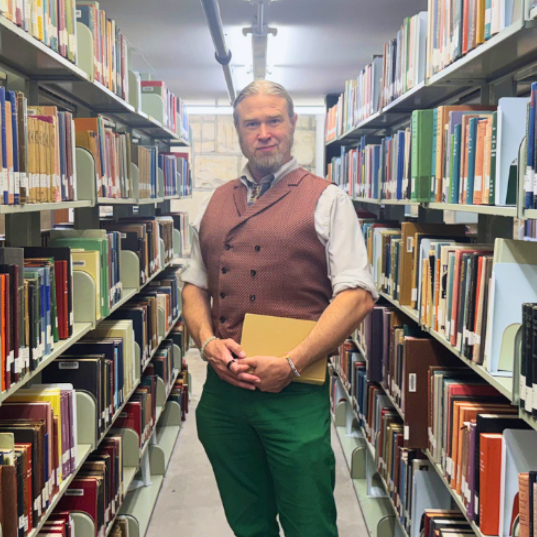 Dan Ireton poses in a row of books in the K-State Libraries