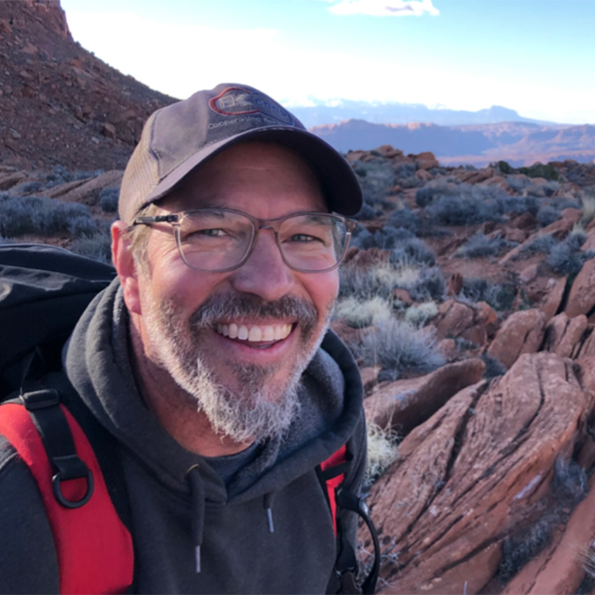 Andrew Hope smiles for a selfie in a canyon.