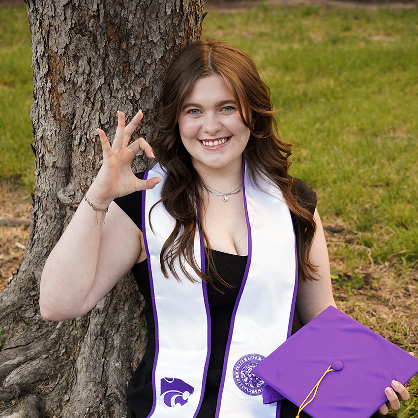 Erin Frenk poses for a portrait while wearing a graduation cap and stole.