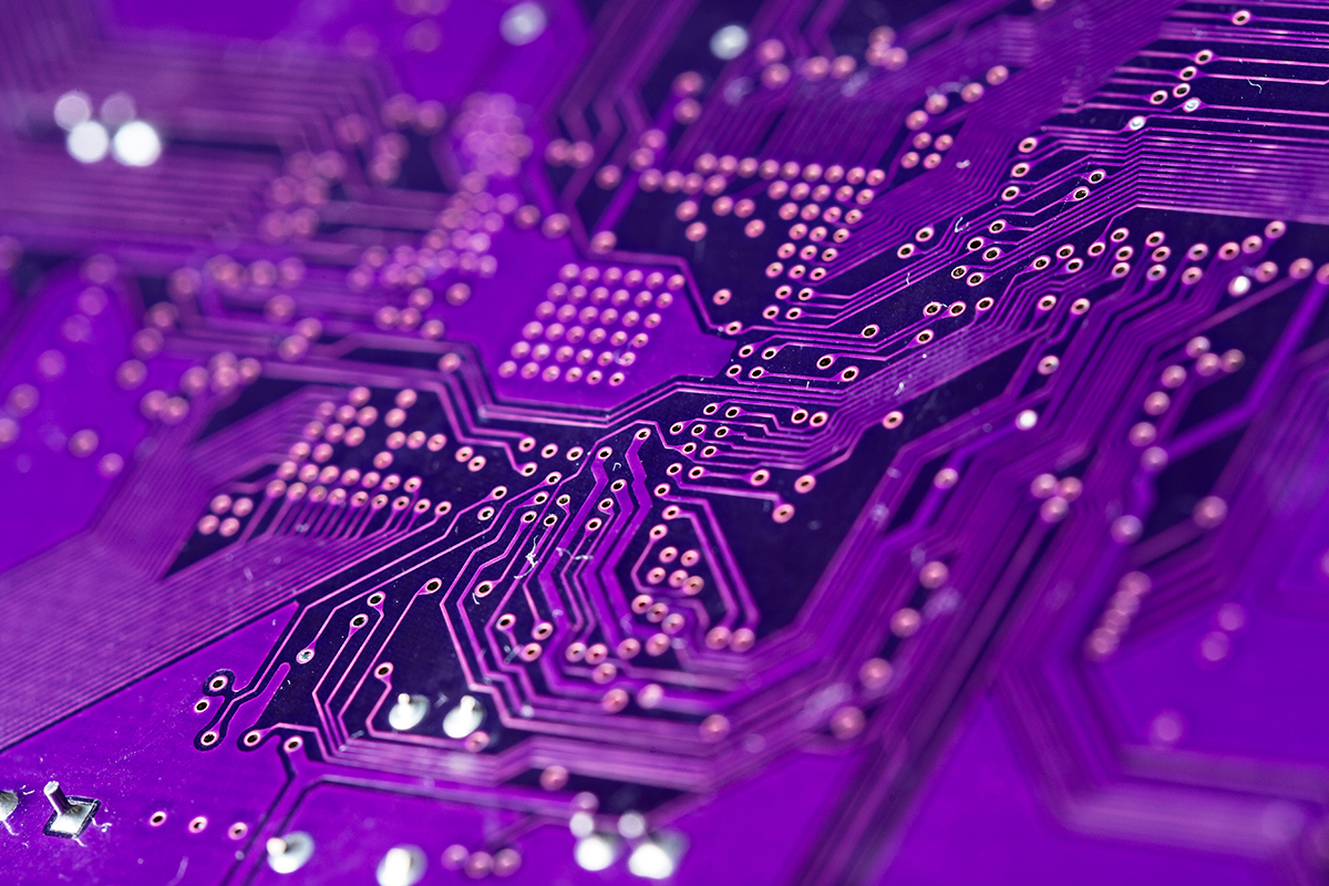 A closeup shot shows the circuits on a purple computer chip.