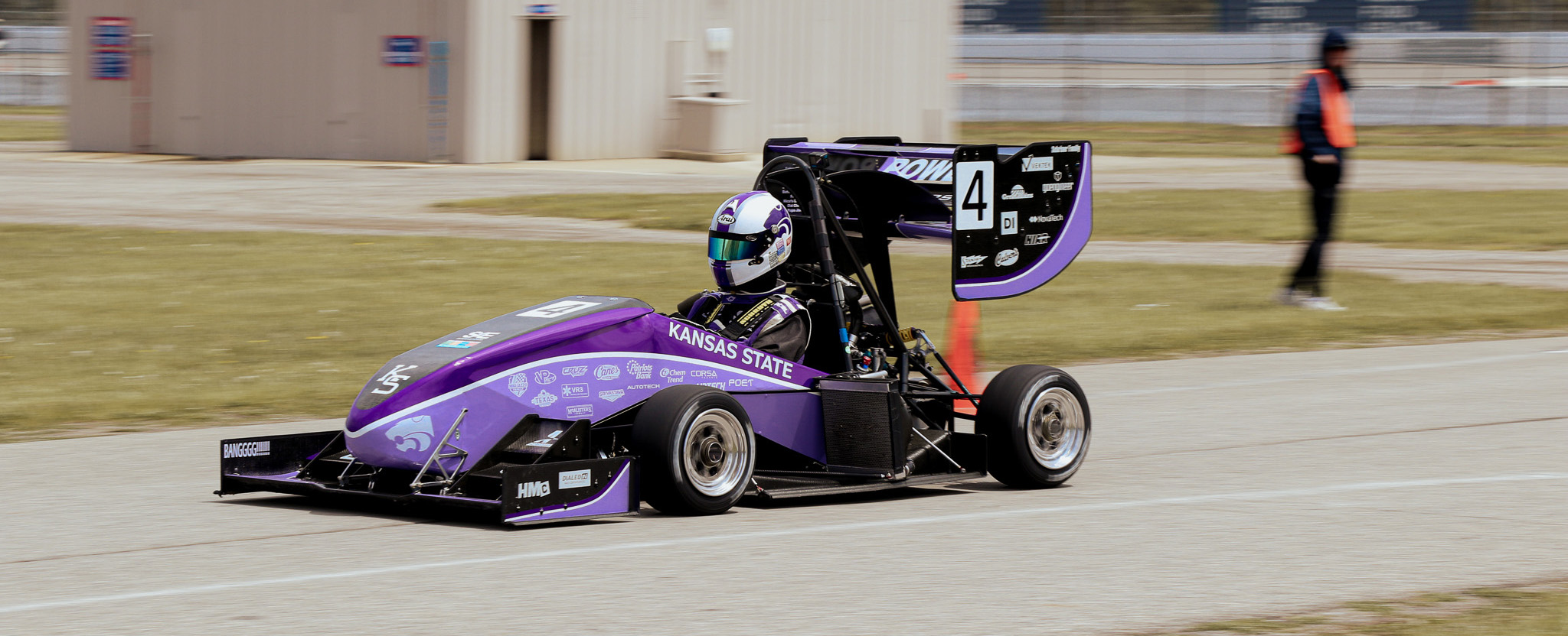 A Formula SAE car decked out in purple races down the track.