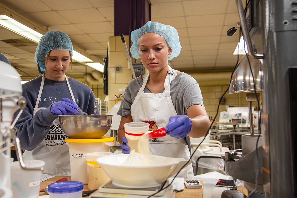Students measure ingredients for a sorghum muffin recipe in a baking lab.