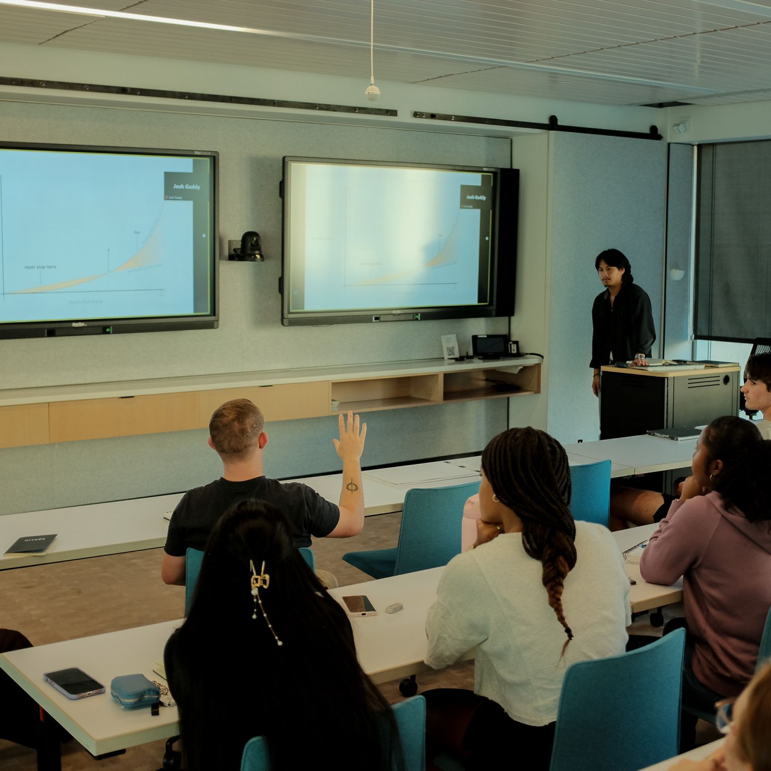 An architecture graduate student gives a presentation on sketching at the head of a college classroom.