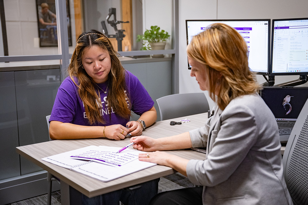 A college student sits with her academic advisor in an office. 