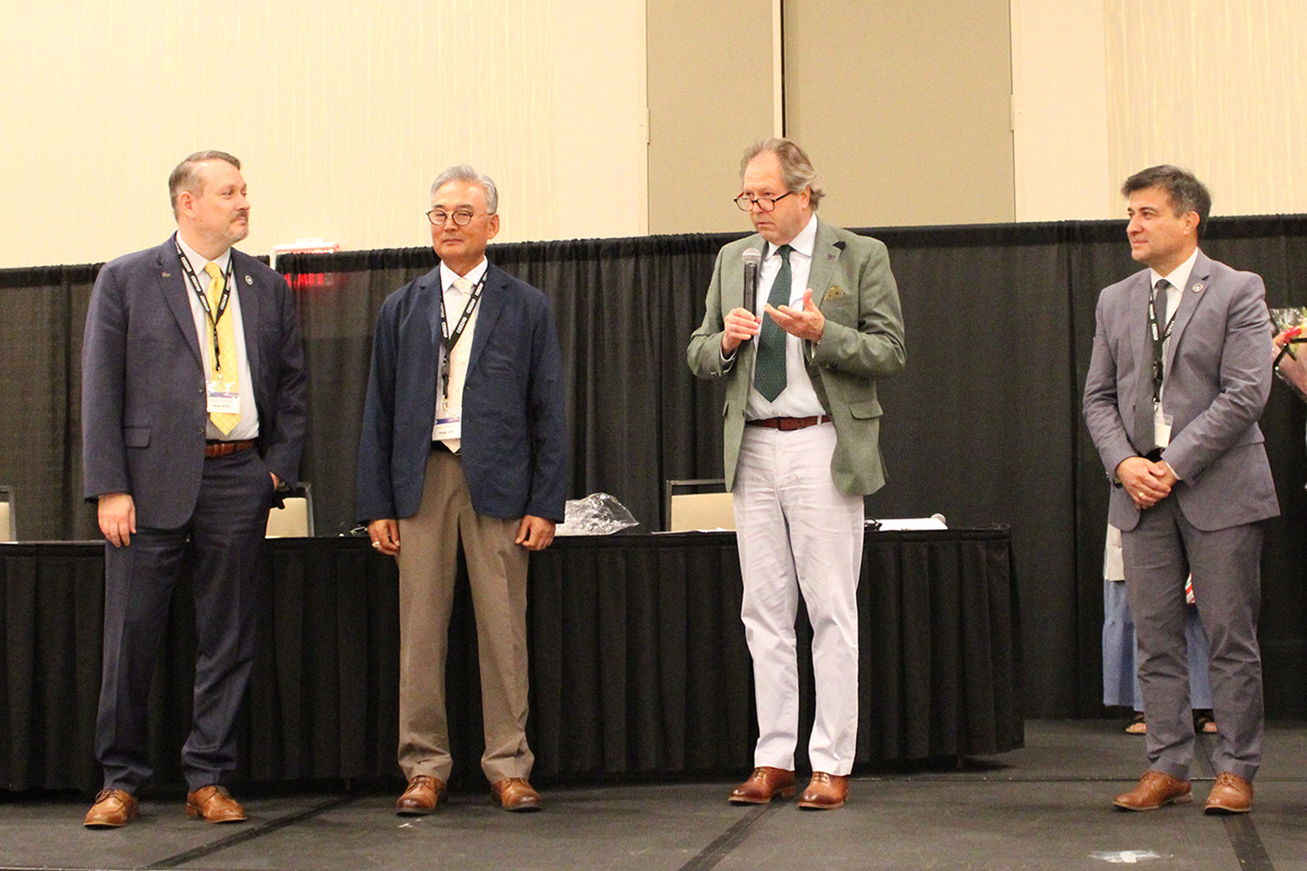Four college-level faculty and researchers stand together in an open forum hall.
