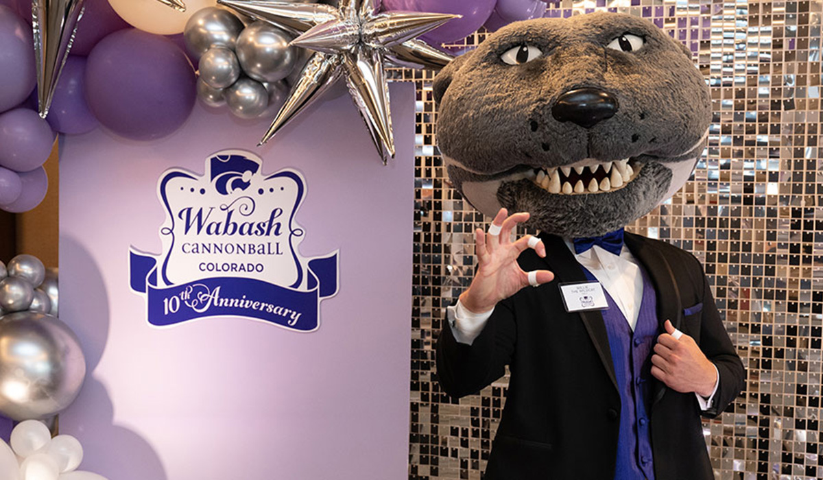 Willie the Wildcat stands beside a balloon arch and decorative sign reading "Wabash Cannonball Colorado: 10th Anniversary"