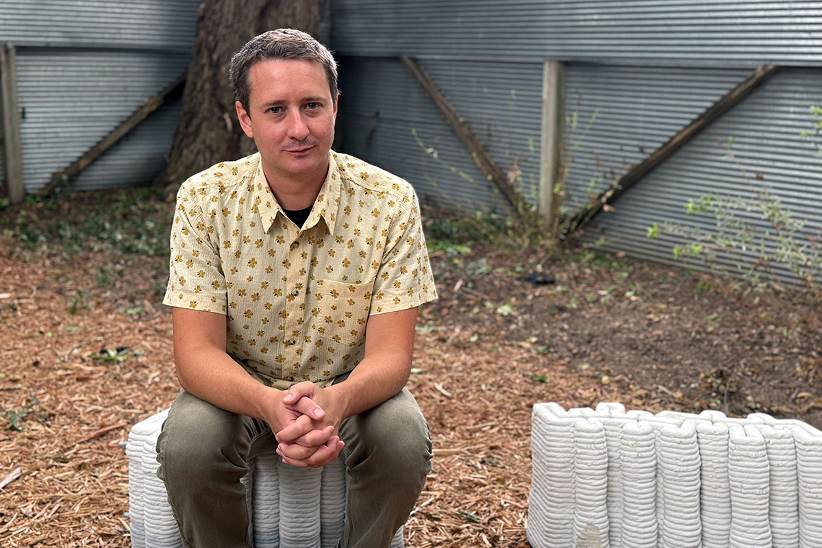 An architecture professor sits on piles of 3D-printed concrete.