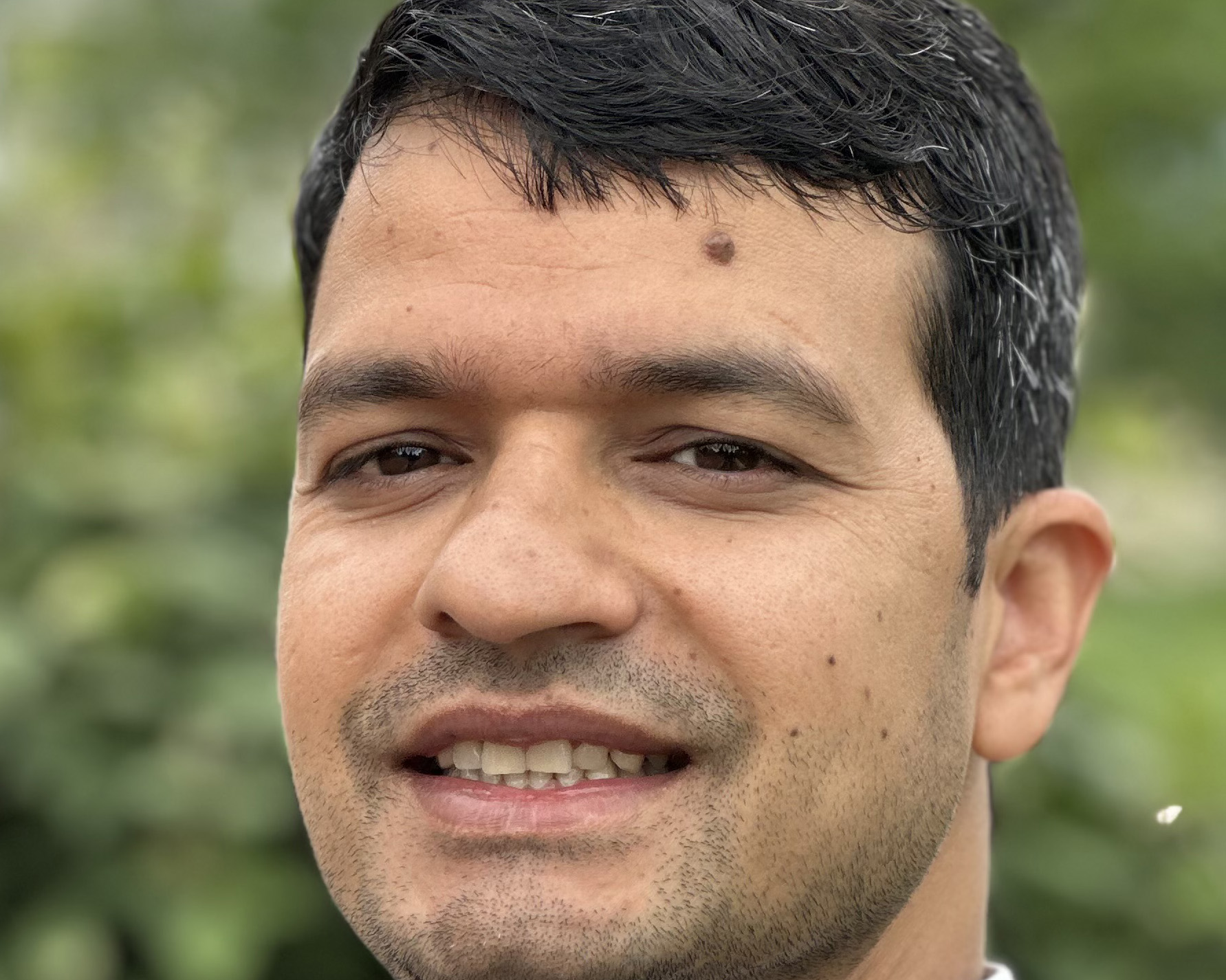 Student smiles for a portrait in front of a green background 
