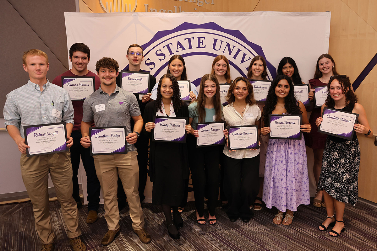 A group of students stands in two rows holding certificates.