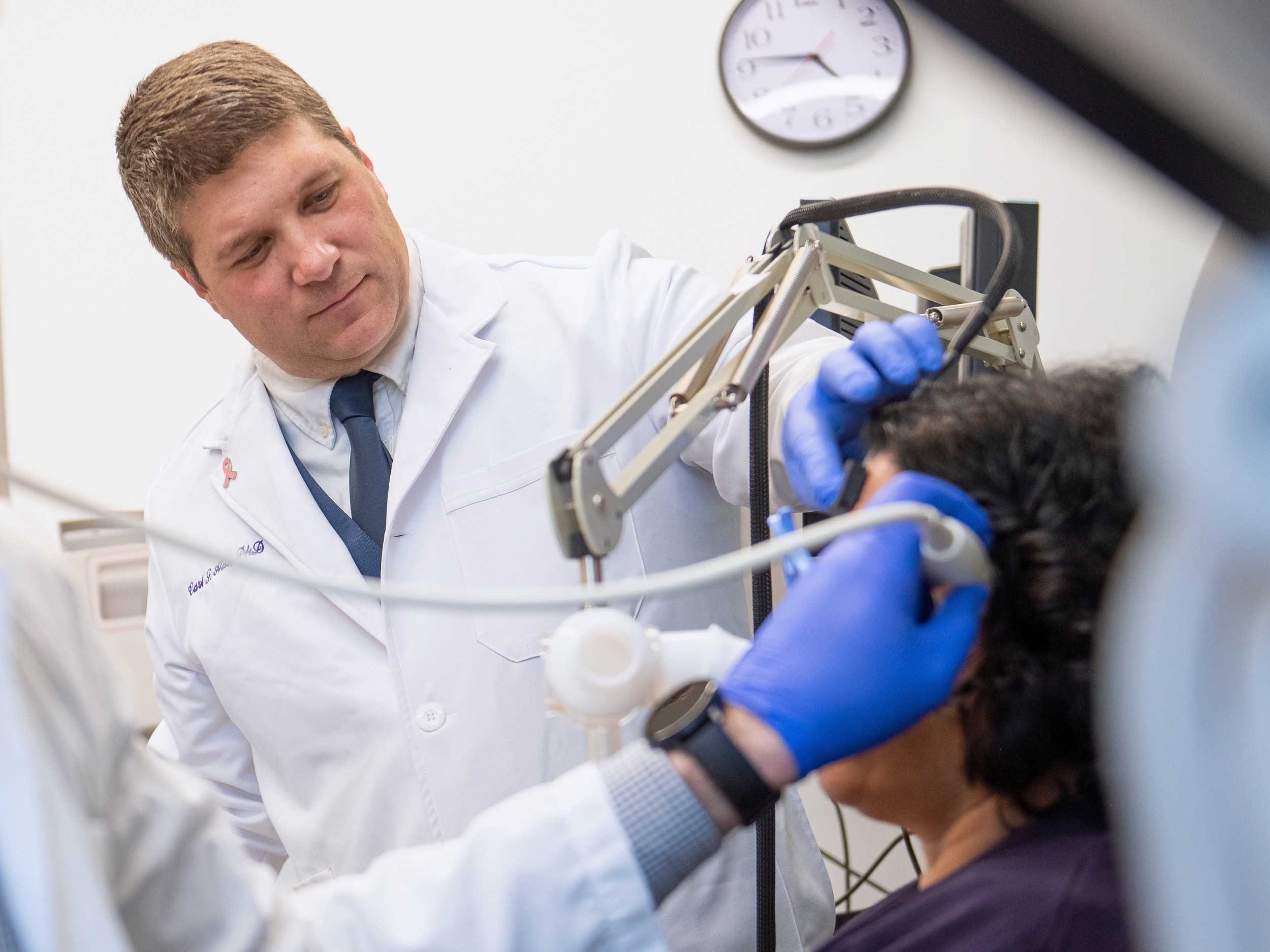 A close of image of Ade, in a white lab coat, working with a patient in one of his research labs.