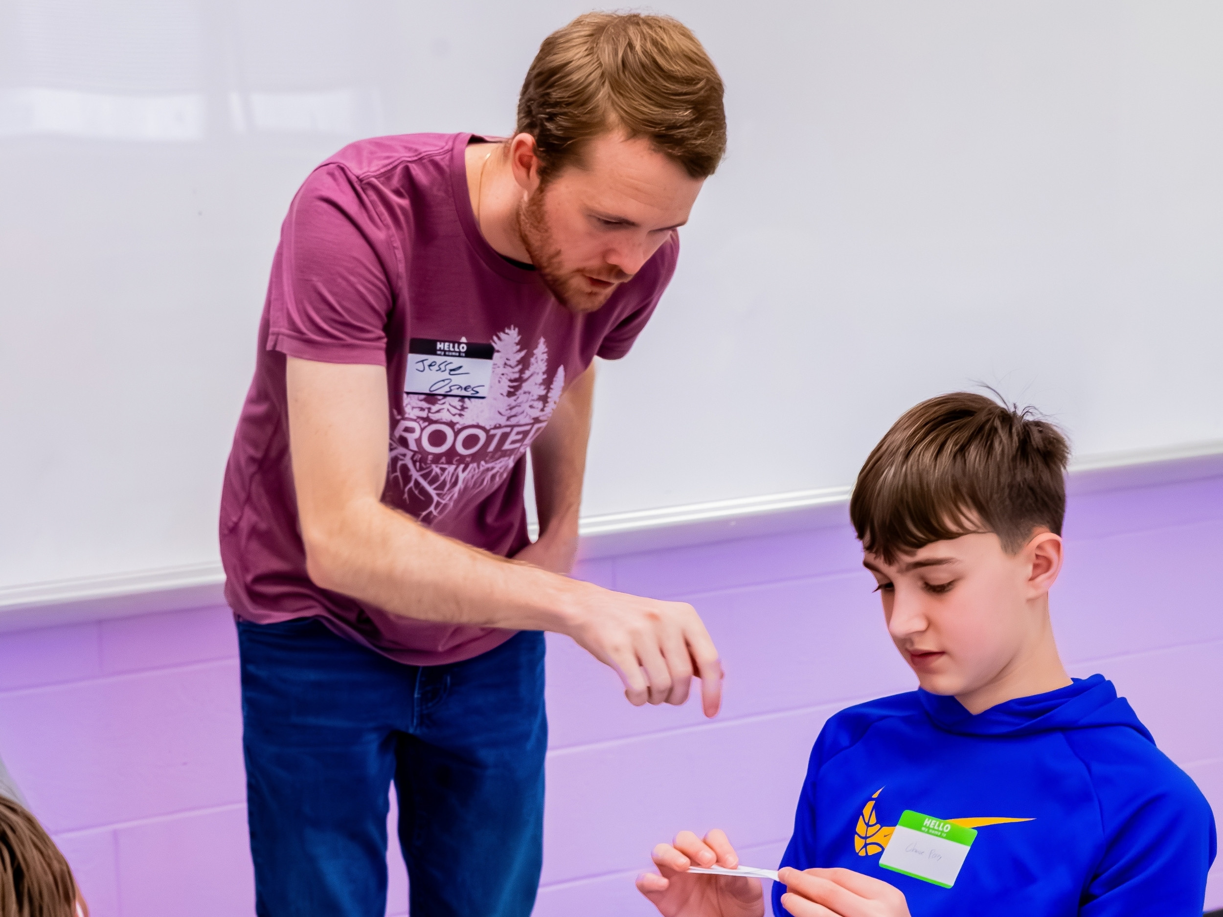 Jesse Osnes works with a student during Sonia Kovalevsky day, pointing to a small puzzle the student is solving.