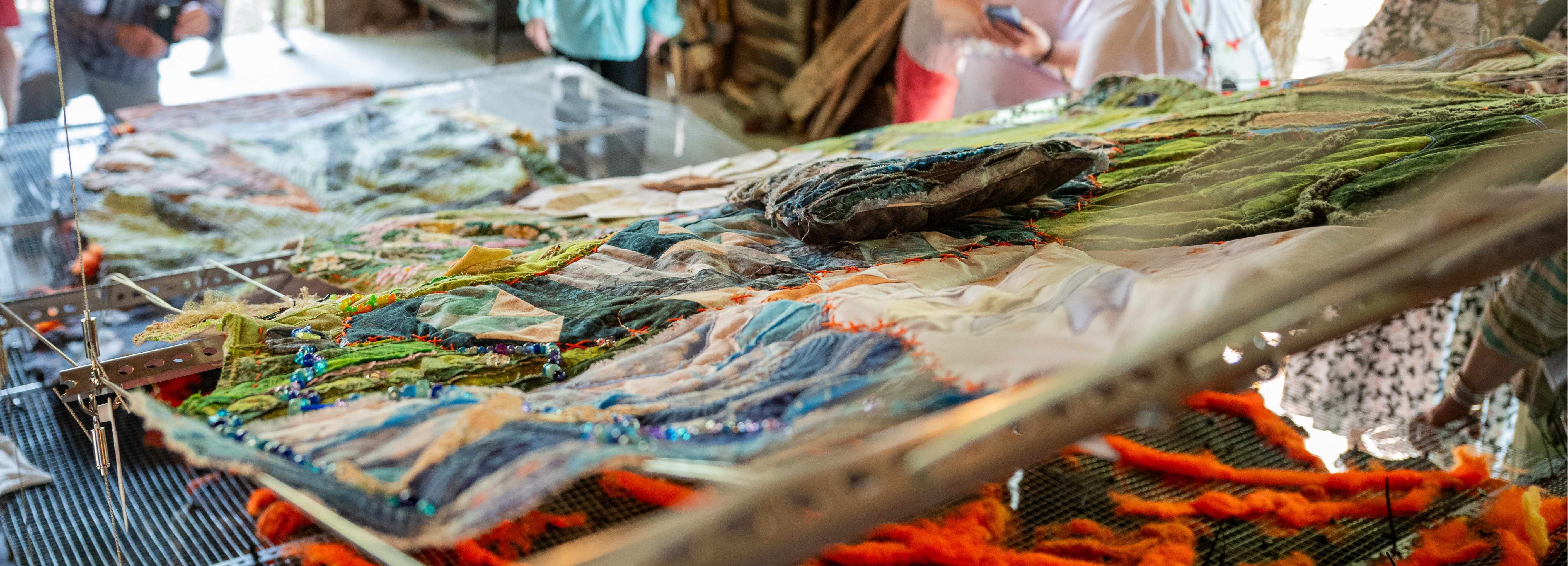 A close up image of 'The ROOT Source' quilt, hanging from a metal apparatus.