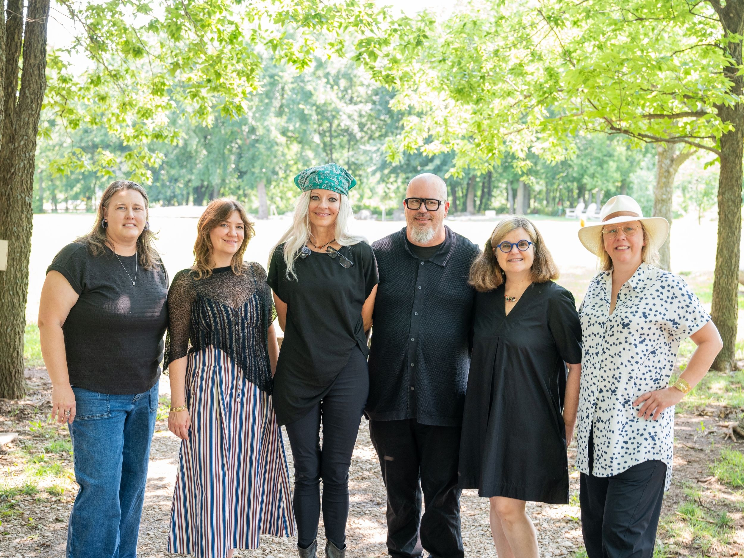 Ursula Emery-McClure, wearing a black t-shirt and green bandana on her head, stands amongst her architectural, design and landscape design colleagues