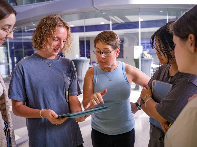 Kaup points to an elevation sketch on an iPad while explaining measuring strategies to a group of students.