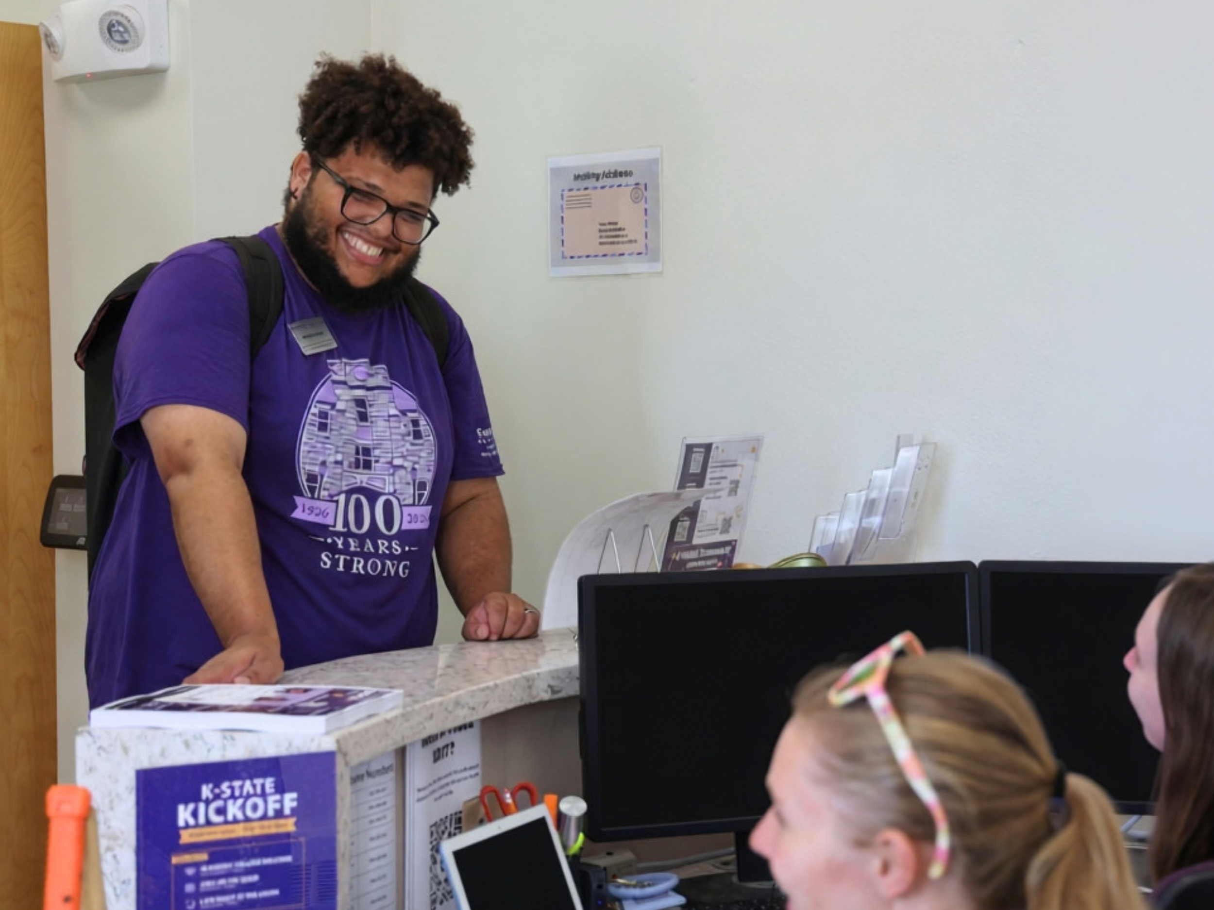 Nathan Dozier stands at a desk at the front of a residence hall, speaking to students sitting on the other side.