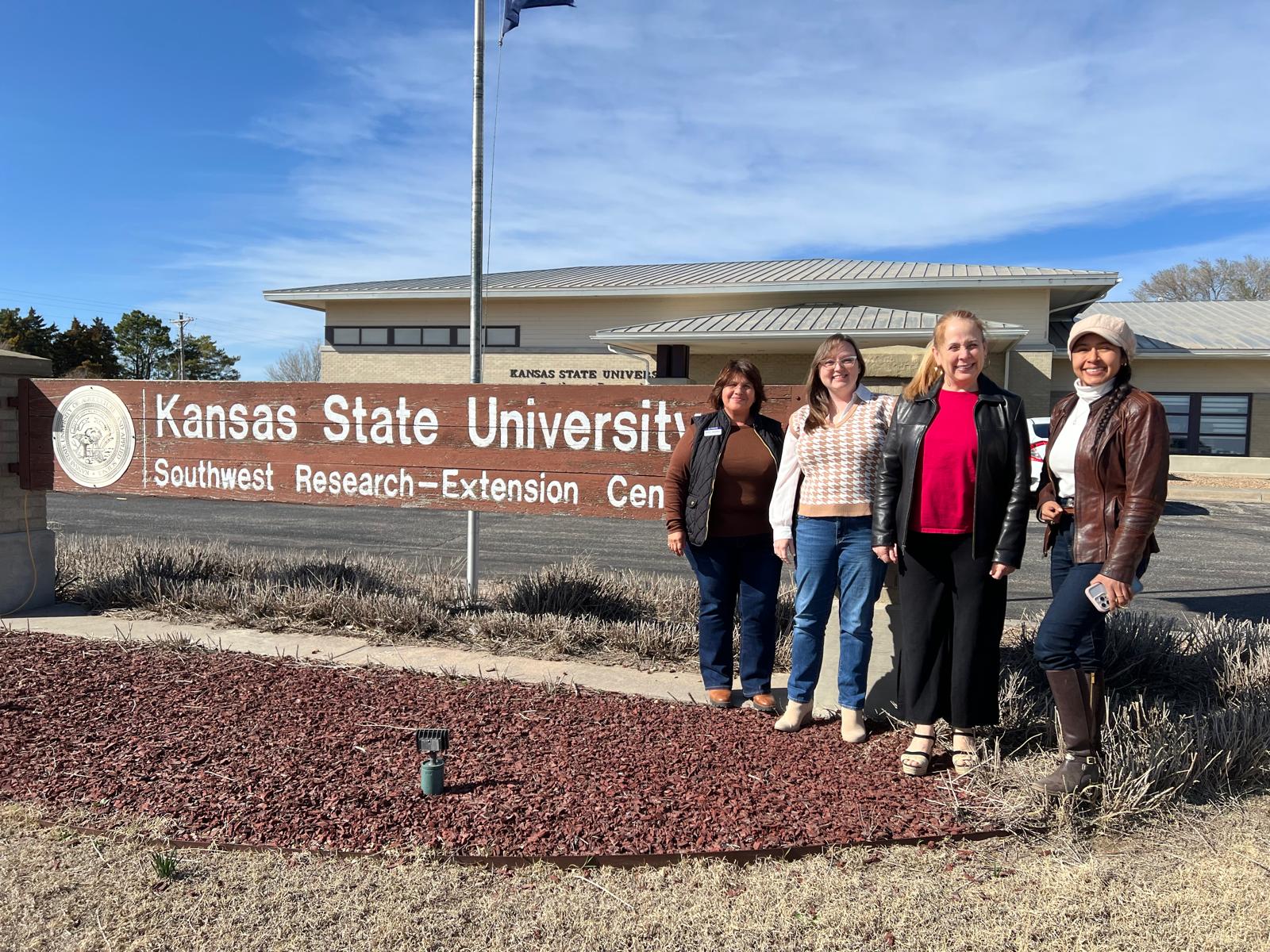 A group of people standing outside in front of a sign for the southwest Kansas extension center.