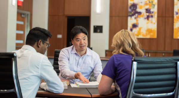 A professor speaks with two students.