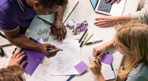 Students sit around a table working on a project