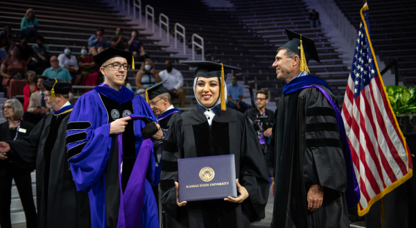 A graduate holds a K-State diploma.