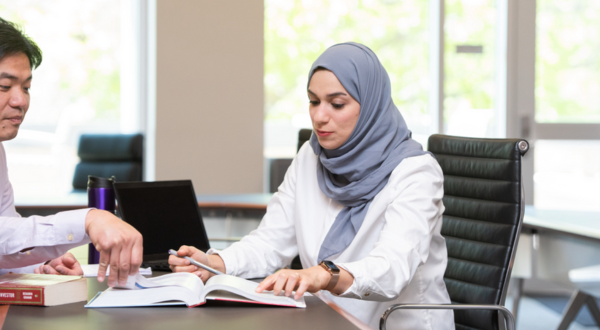 Two students look at a textbook.