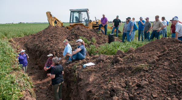 A specialist speaks to a crowd in a field.