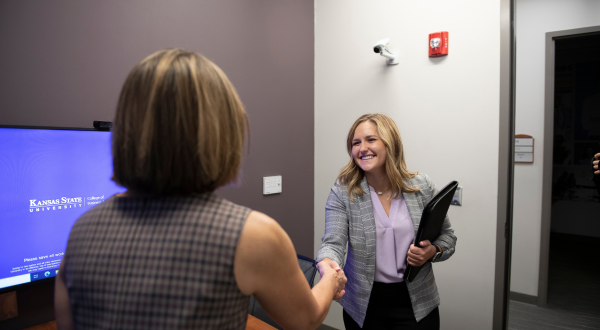 Two women shake hands.