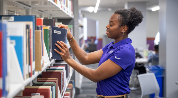 A student shelves books in Hale Library.