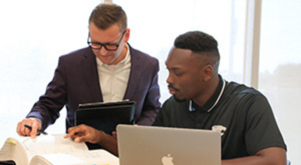 An instructor and student looking at a textbook.