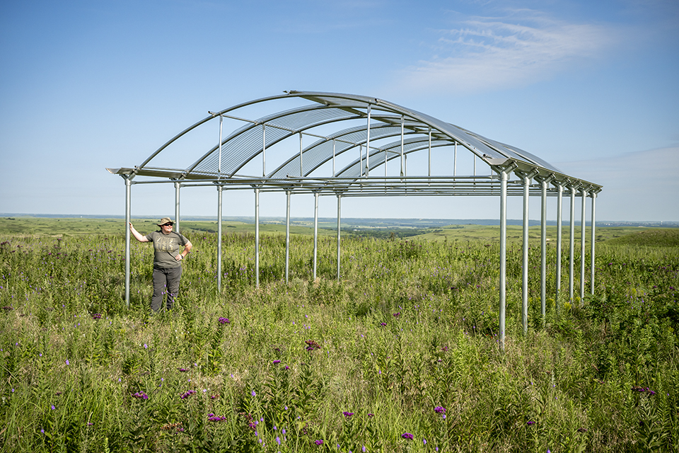 Structure on prairie with a partially open roof. 