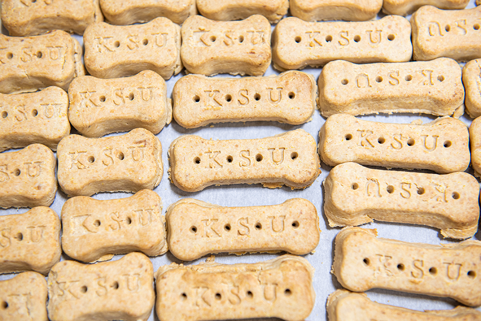 Several rows of pet biscuits are aligned, each with the letters KSU imprinted on them.