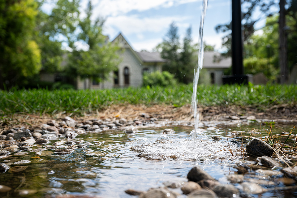 A stream of water from a spigot in front of a house