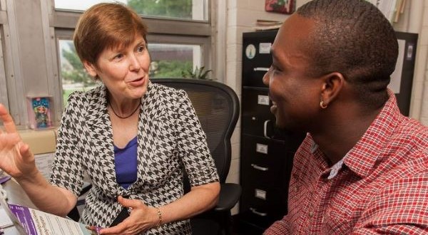 female with short red hair in a black and white checkered jacket talking with a male in read shirt 