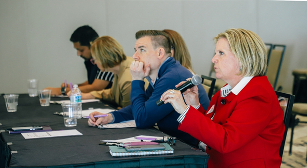 a panel of judges are seated at a table and listening to presentations